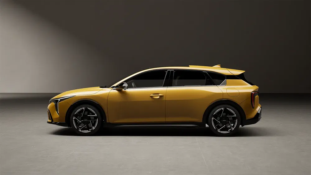Profil latéral du SUV électrique Aiways U6 en jaune, dans un environnement industriel.