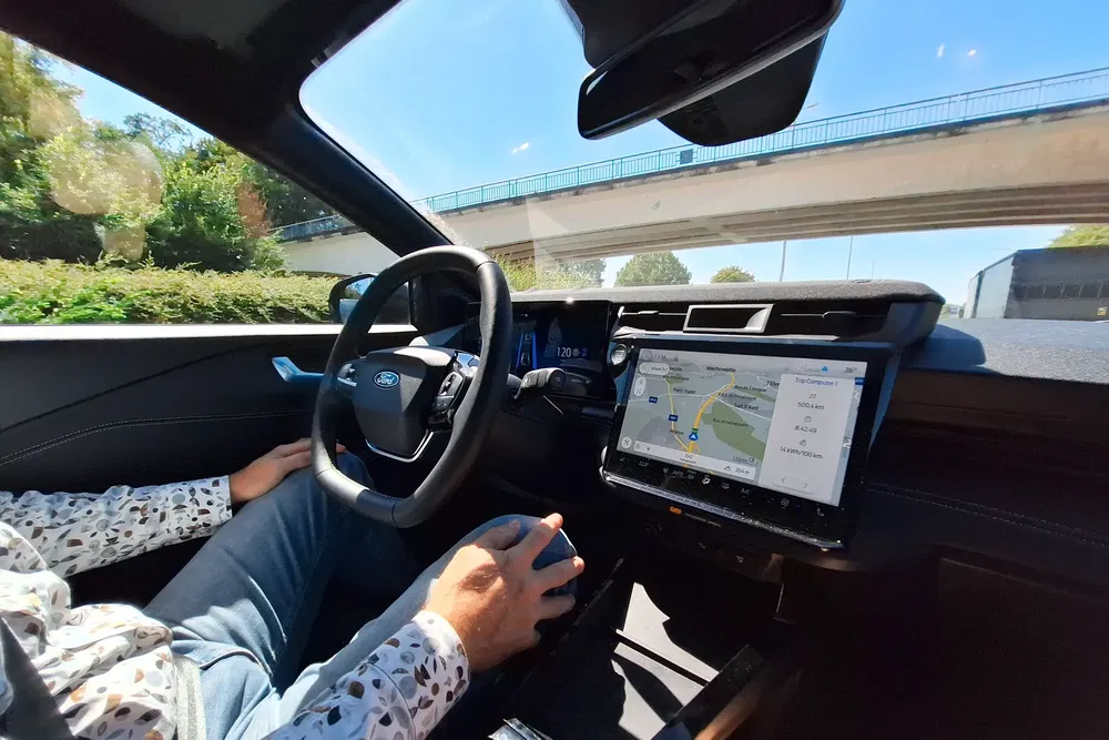 Intérieur d'une Ford avec GPS affiché sur écran, conducteur main sur le volant.