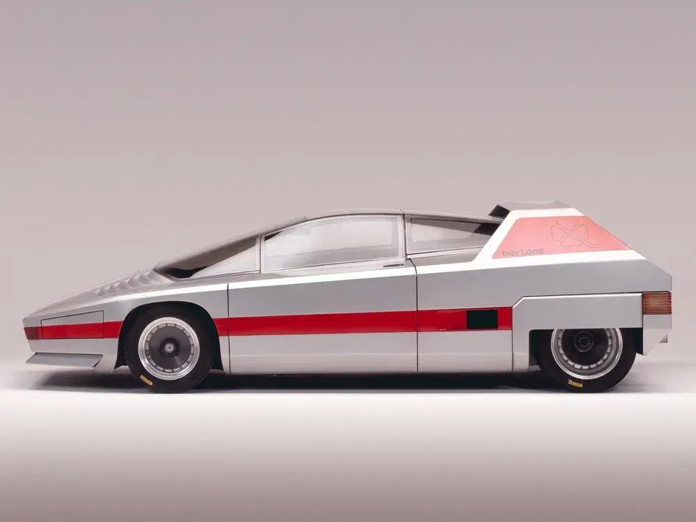 {"fr":"Prototype Bertone futuriste argent avec bande rouge, design angulaire et roue arrière unique.","nl":"Futuristische zilveren Bertone prototype met rode streep, hoekig ontwerp en unieke achterwiel."}
