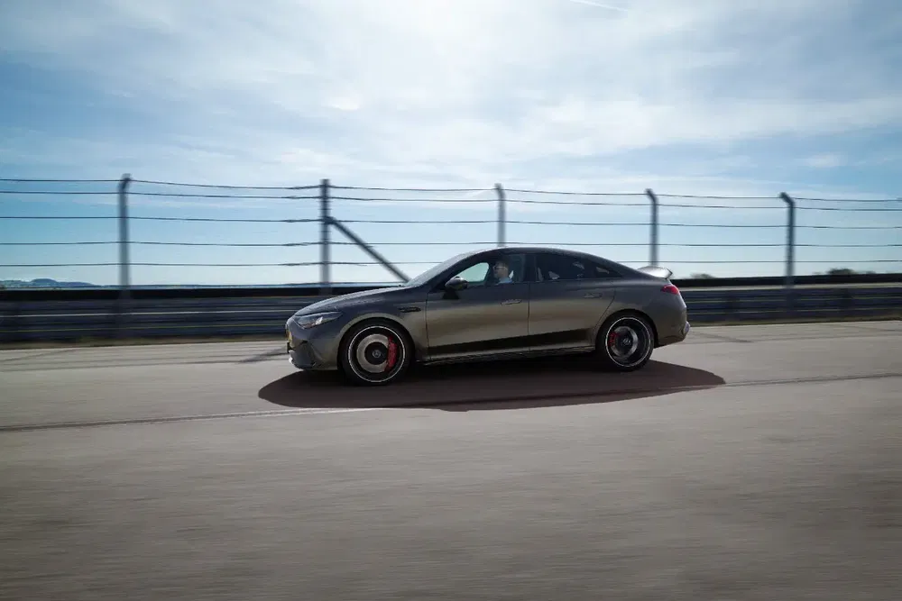 Mercedes-Benz AMG EQE rijdt op circuit met heldere lucht op de achtergrond.