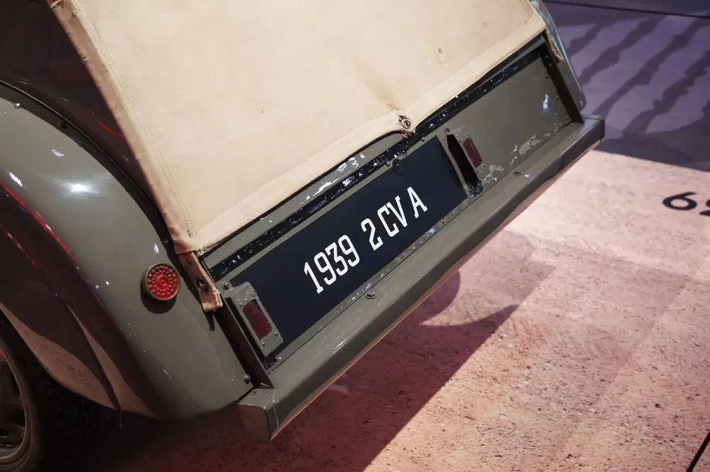 Citroën 2CV 1939 avec plaque d'immatriculation rétro et carrosserie grise en exposition.