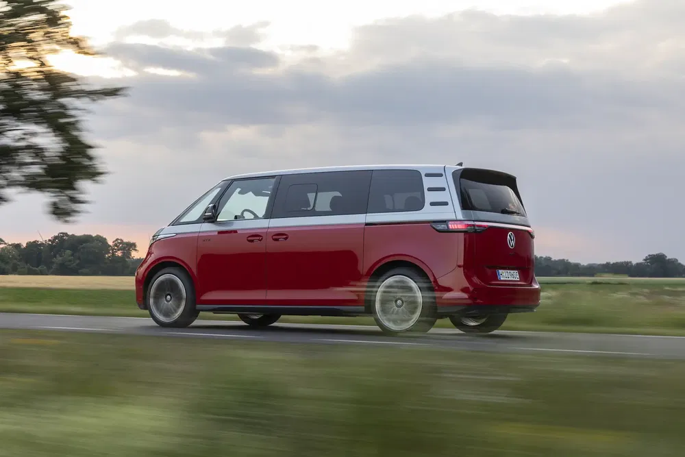 Van Volkswagen ID.Buzz rouge sur une route de campagne au coucher du soleil.