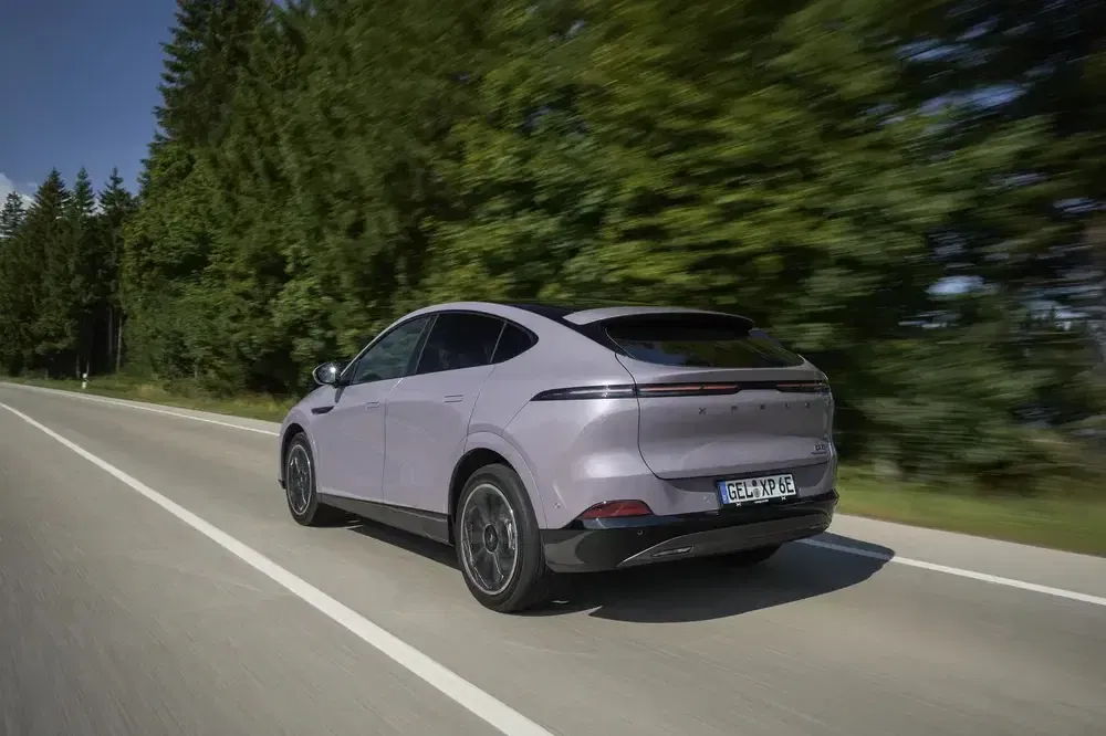 SUV électrique sur une route bordée d'arbres, mettant en avant son design aérodynamique.