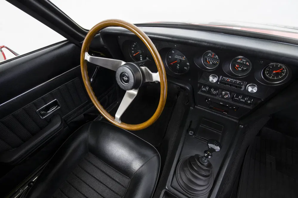 Interieur van een klassieke Opel auto met houten stuur en vintage dashboard.