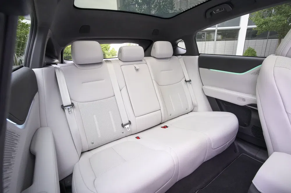 Intérieur arrière d'un VUS électrique moderne avec sièges en cuir blanc et toit panoramique.