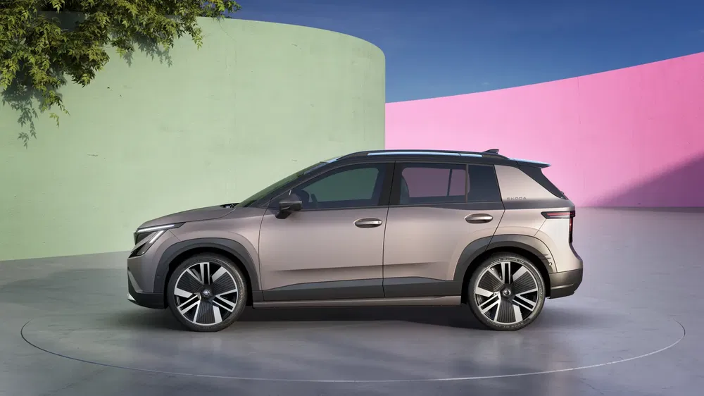 SUV moderne Kia EV5 stationné, arrière-plan rose et vert, ciel bleu clair.