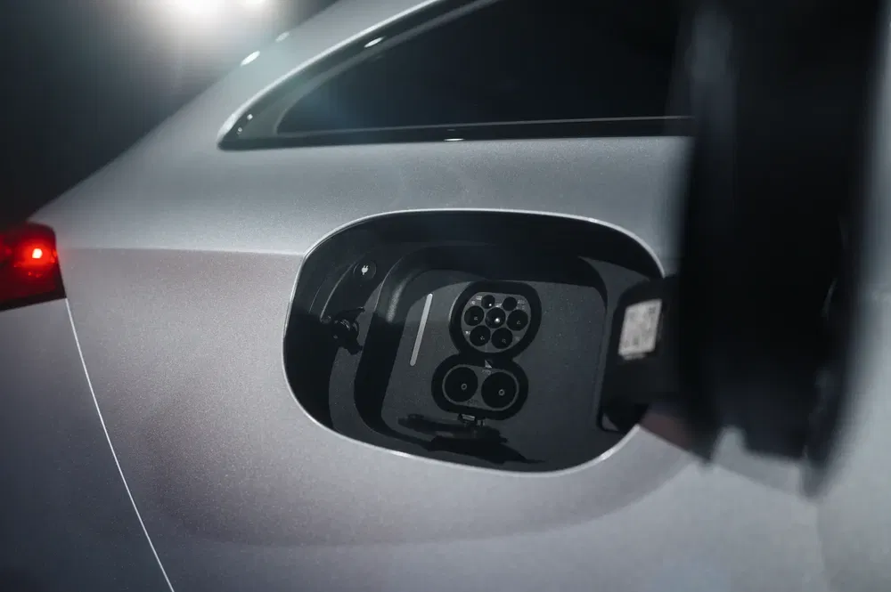 Oplaadpoort van een moderne grijze elektrische auto onder zacht licht.