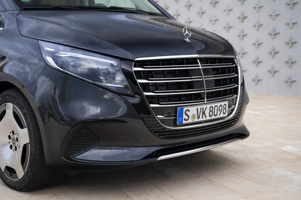 Close-up van een Mercedes-Benz V-Klasse met opvallend chromen grille en stijlvolle koplampen.