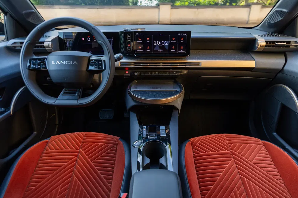Moderne Lancia-interieur met rode textuurstoelen en geavanceerd digitaal dashboard.