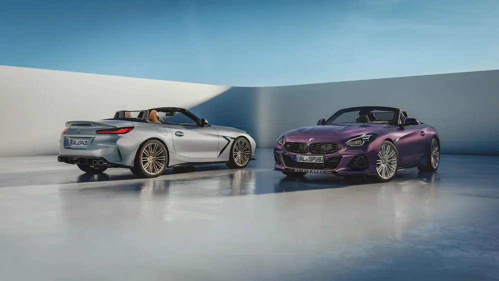 Deux BMW Z4 Alpina S1 cabriolets, l'un gris et l'autre violet, stationnés côte à côte.