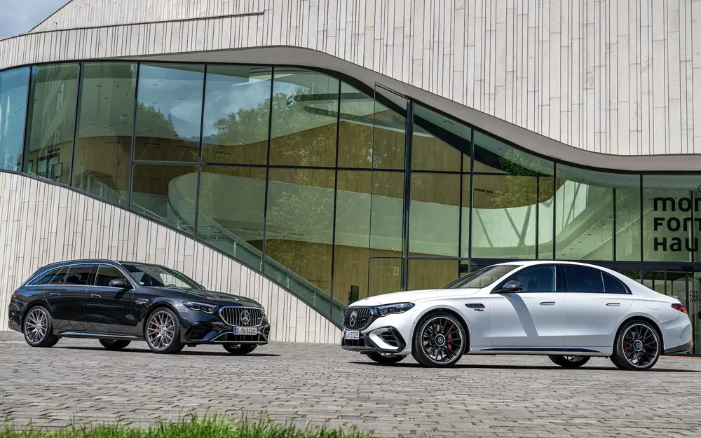 Mercedes-AMG E63 wagons devant architecture moderne, modèles noir et blanc côté à côte.