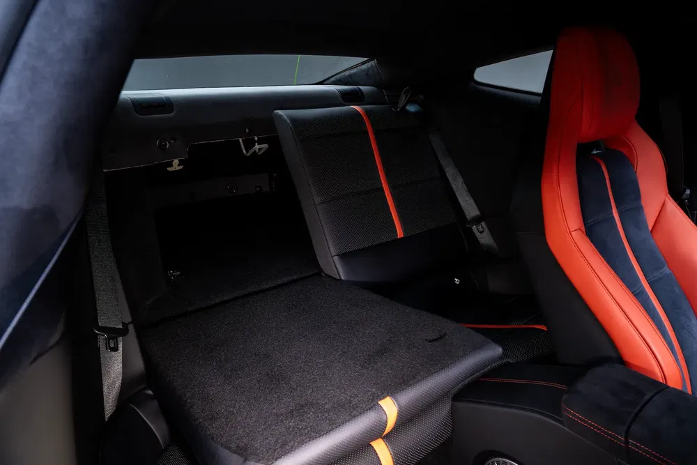 Intérieur de voiture de sport avec sièges en cuir noir et rouge, et espace de chargement modulable.