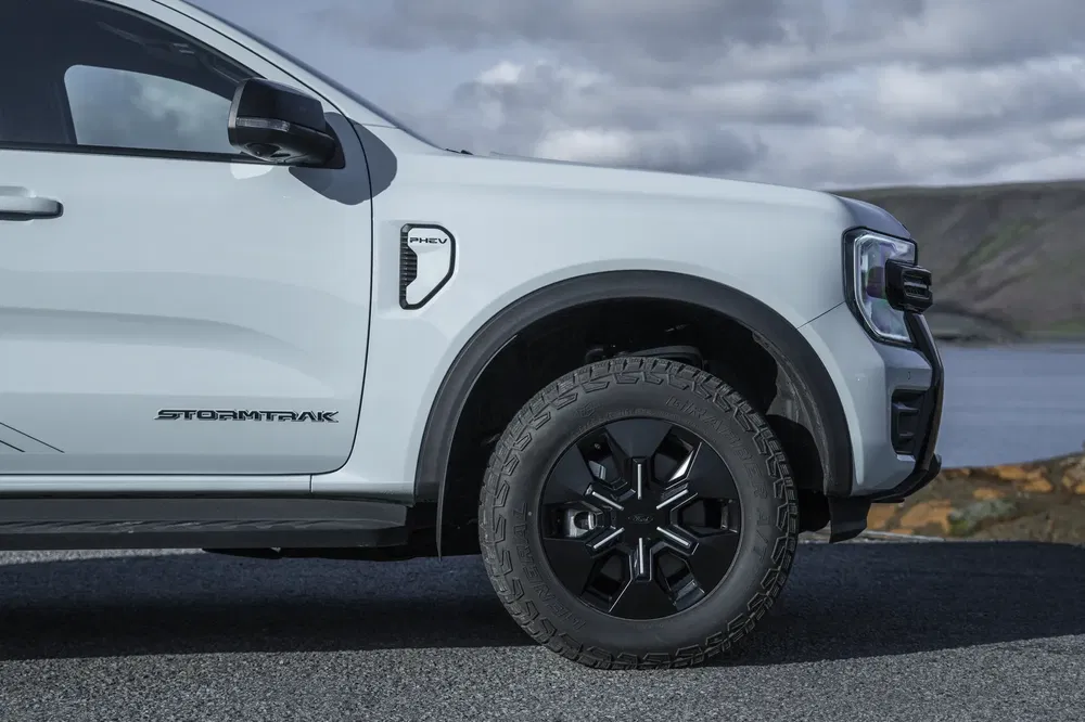 Zijaanzicht van een Ford Ranger Stormtrak PHEV met zwarte offroad wielen.