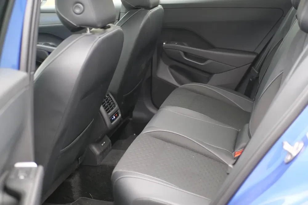 Achterbank van auto, zwarte lederen stoelen, stijlvolle armleuningen, ruime beenruimte.