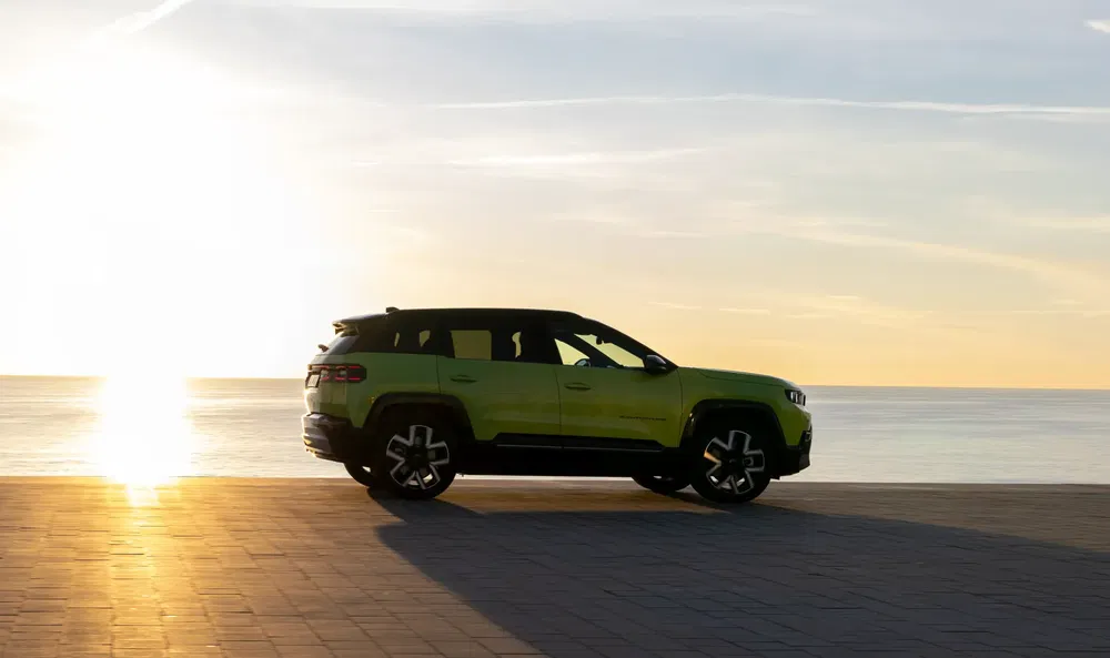 Groene SUV aan zee bij zonsondergang, modern en stijlvol ontwerp.