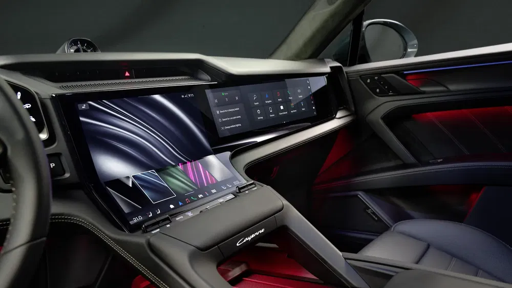 Intérieur high-tech de la Porsche Cayenne avec double écran tactile et éclairage d'ambiance rouge.