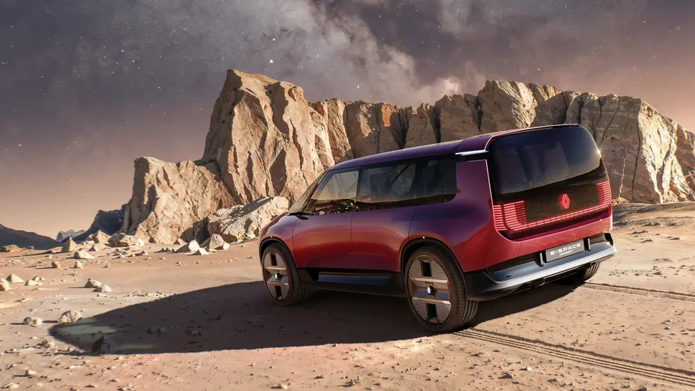 Renault Espace SUV rouge sur terrain désertique avec montagnes rocheuses en arrière-plan.