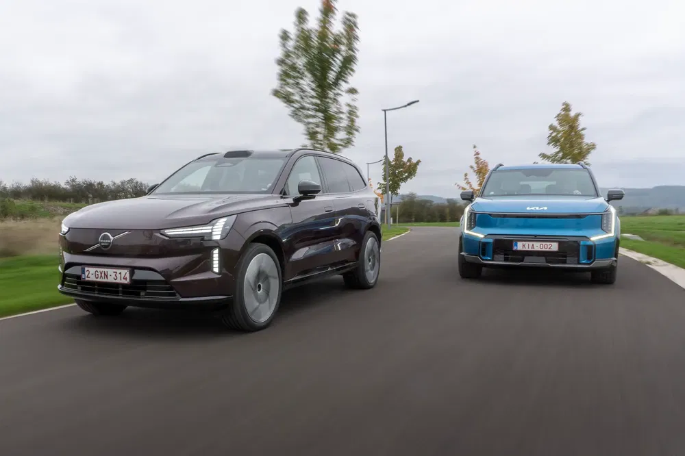 Volvo XC90 brun et Kia bleu roulant côte à côte sur route dégagée.