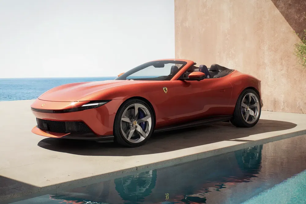 Rode Ferrari Portofino M langs een zwembad met uitzicht op de oceaan.