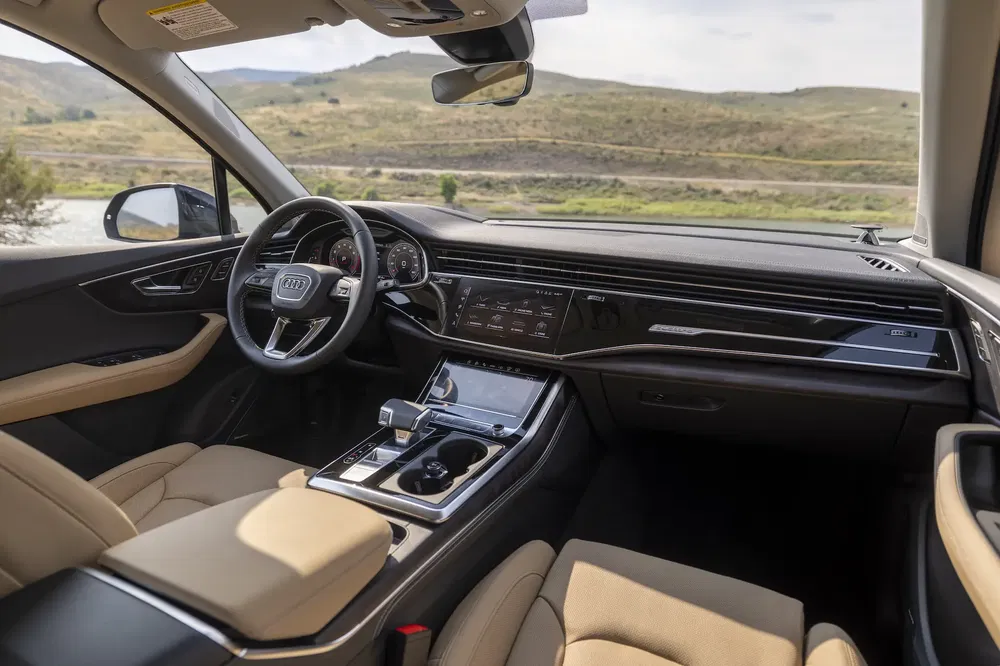 Intérieur luxueux d'une Audi A8 avec tableau de bord high-tech et sièges en cuir beige.