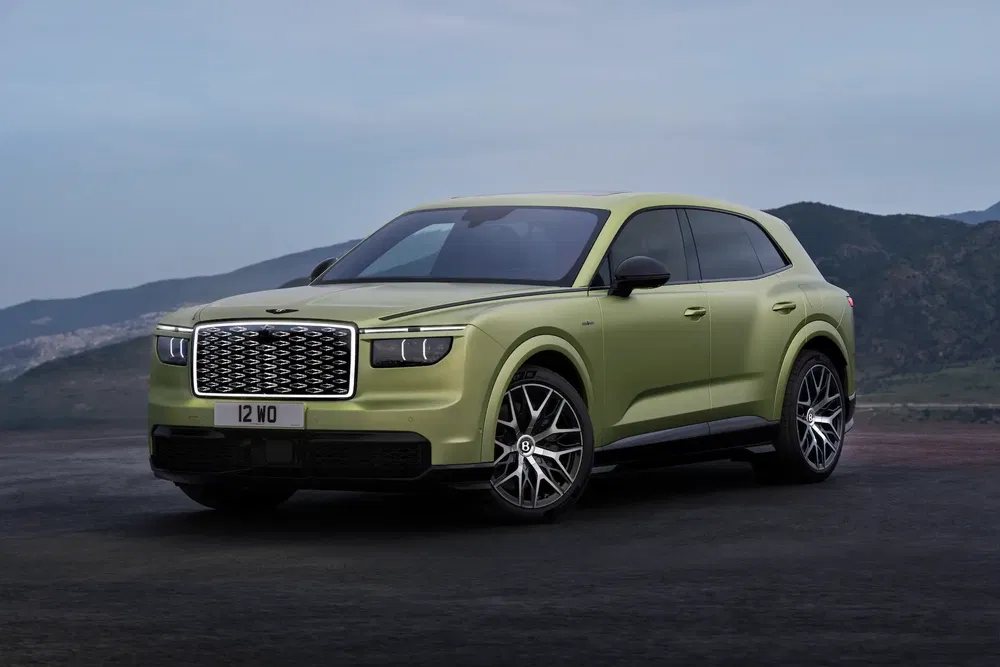 SUV vert Bentley sur fond de montagne, calandre imposante et jantes sportives.