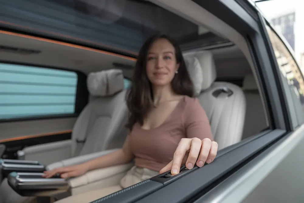 Vrouw in luxe auto-interieur met bedieningsknop, modern en stijlvol.