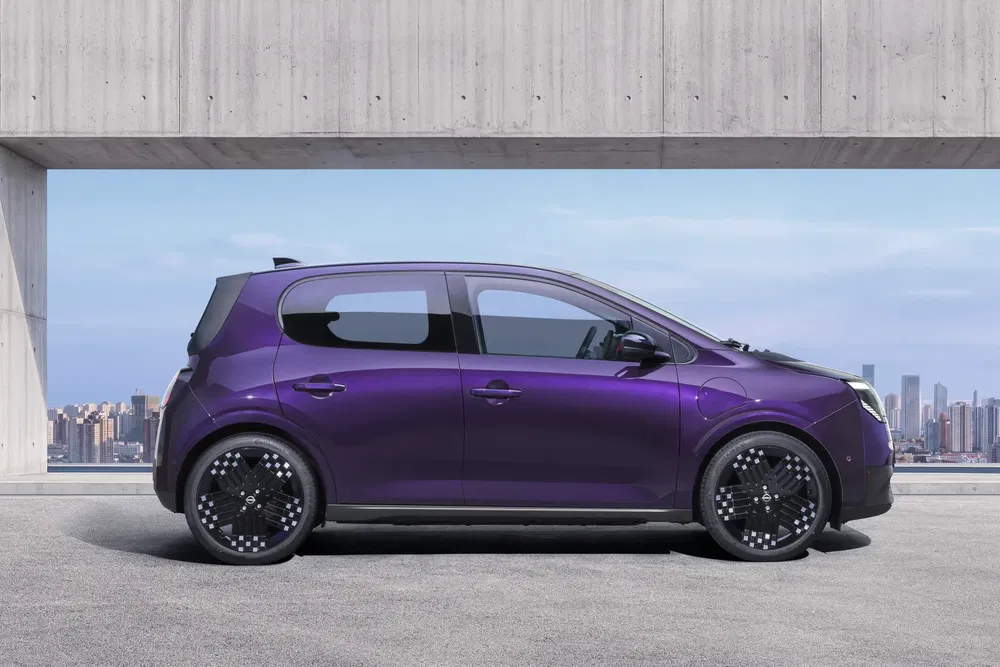 Voiture électrique compacte violette avec jantes noires devant un paysage urbain.