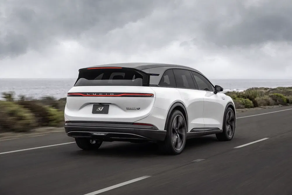 Elektrische auto Lucid Air rijdt op kustweg, witte achterkant en strak design.