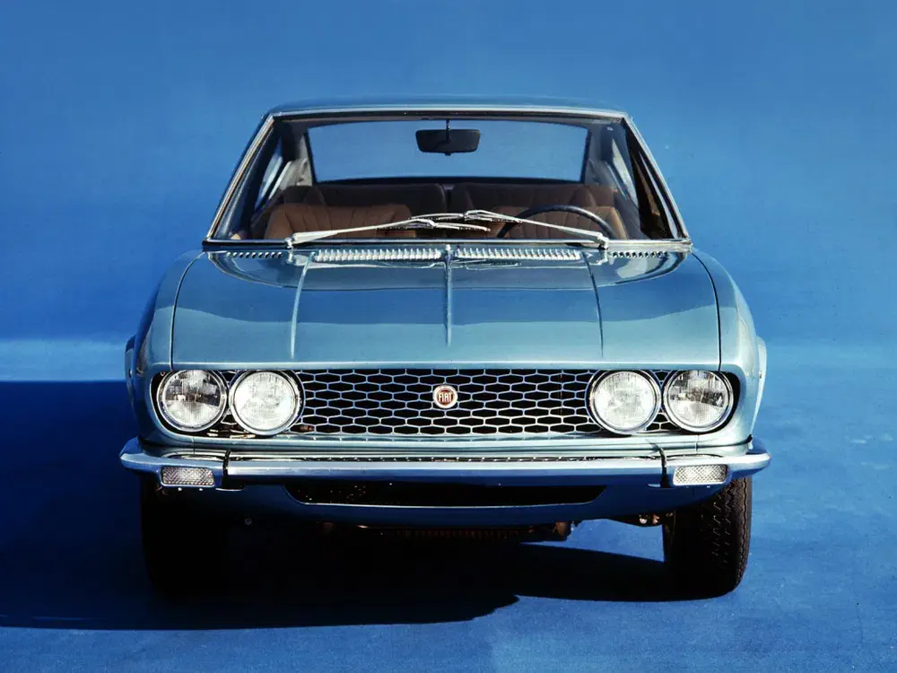 Voiture classique Fiat 124 Sport Coupé de face sur fond bleu vif.