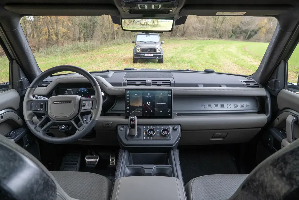 Intérieur moderne du Land Rover Defender avec écran tactile, extérieur de Jeep en arrière-plan.