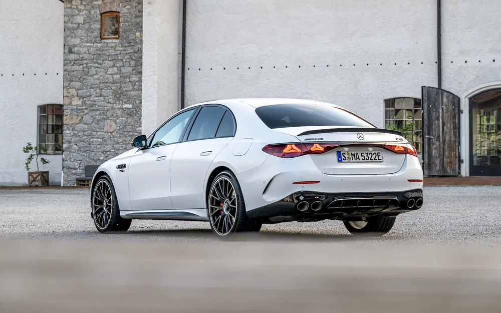 Mercedes AMG blanc garé devant bâtiment, design élégant et sportif, arrière imposant.