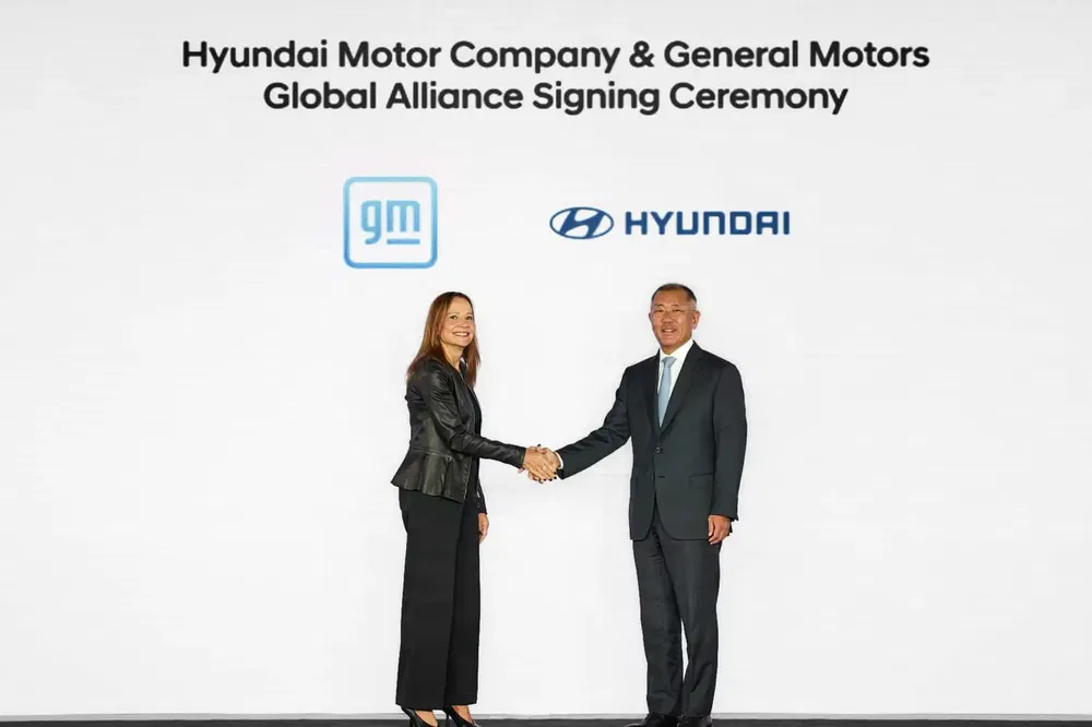 Cérémonie de signature d'alliance entre Hyundai et General Motors avec dirigeants se serrant la main.