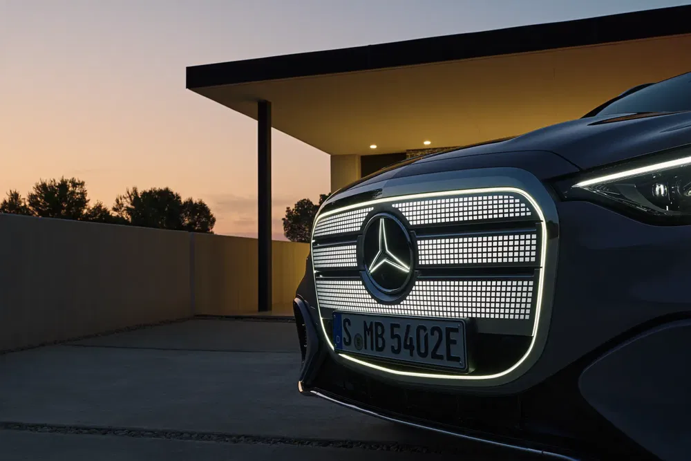 Verlichte grille van de Mercedes-Benz EQS voor een modern huis bij schemering.