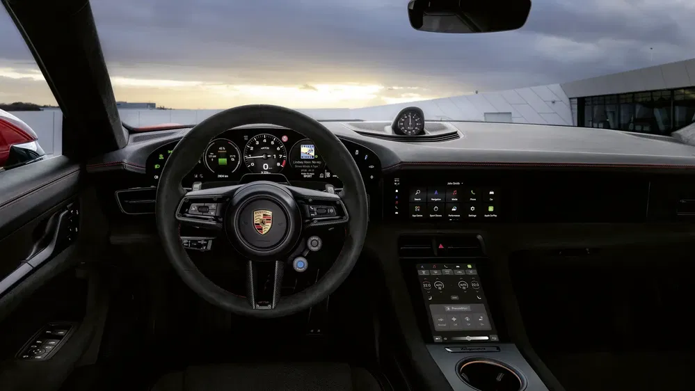 Intérieur moderne de la Porsche Taycan avec tableau de bord numérique et volant sportif.