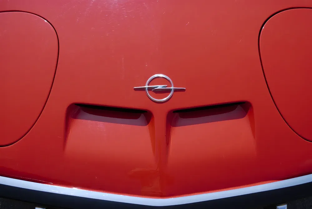 Rode motorkap van een Opel GT met centraal geplaatst iconisch logo.