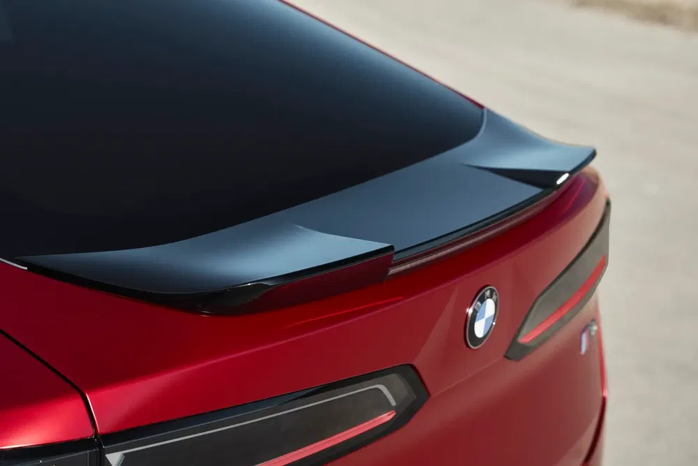 Arrière d'une BMW rouge avec spoiler aérodynamique sophistiqué, éclairage moderne LED.