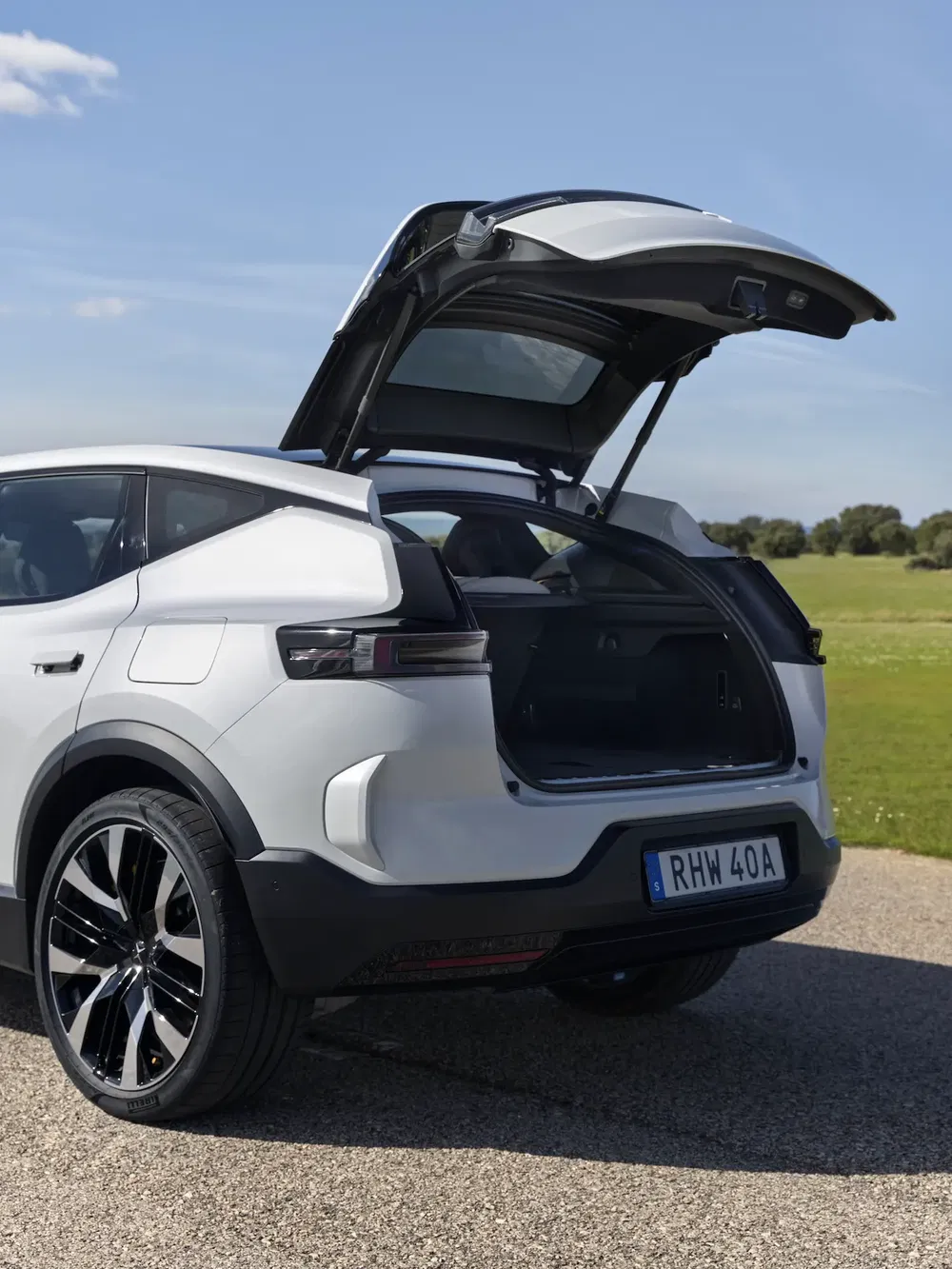 Coffre ouvert d'une voiture électrique élégante sur fond champêtre.