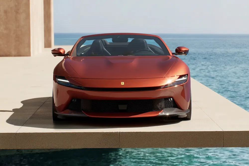 Rode Ferrari Purosangue met uitzicht op de oceaan, elegante en moderne uitstraling.