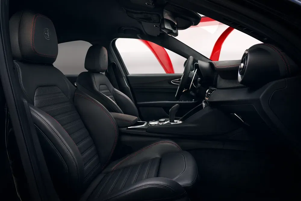 Intérieur luxueux de l'Alfa Romeo Giulia avec sièges en cuir noir et surpiqûres rouges.