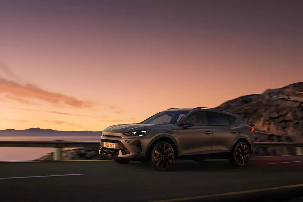 SUV Cupra Formentor roulant au coucher du soleil sur une route de montagne panoramique.