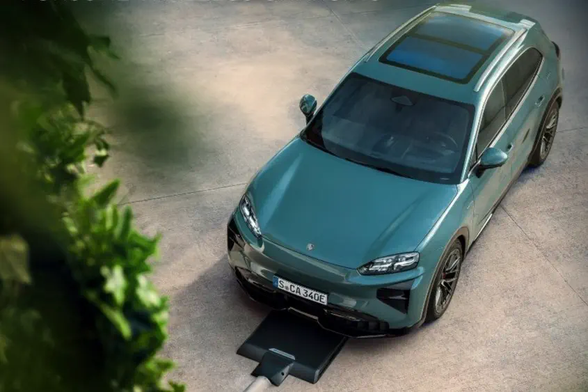 Porsche électrique chargée sans fil sur une allée, cadre verdoyant.