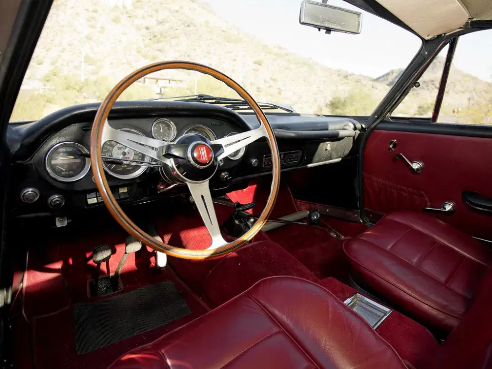 Intérieur Fiat classique avec sièges en cuir rouge et volant en bois élégant.