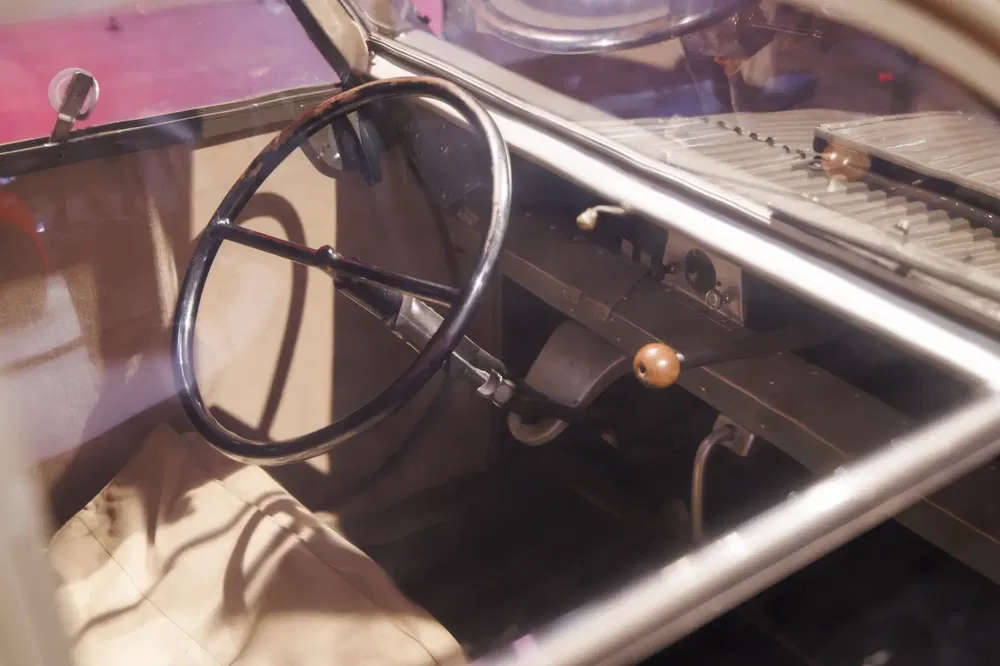 Intérieur d'une Citroën 2CV historique, volant et tableau de bord rétro en évidence.