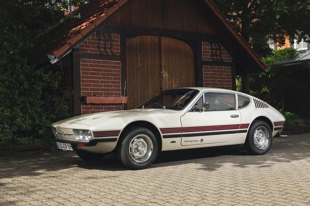 Volkswagen SP2 blanche stationnée devant un garage en bois, design vintage et classique.