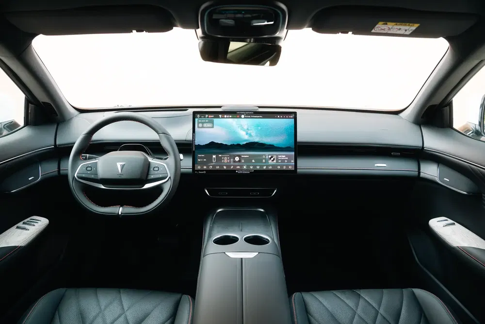 Intérieur high-tech d'une voiture électrique, volant unique et grand écran tactile central.