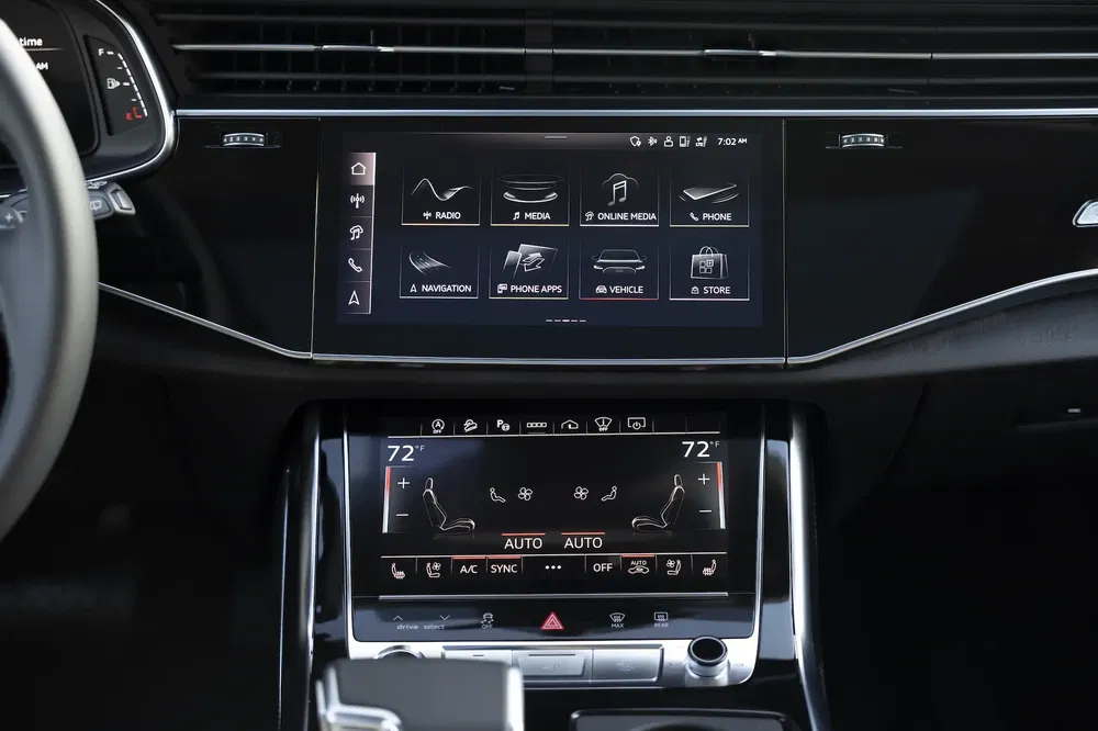 Intérieur d'Audi avec double écrans tactiles pour navigation et climatisation.