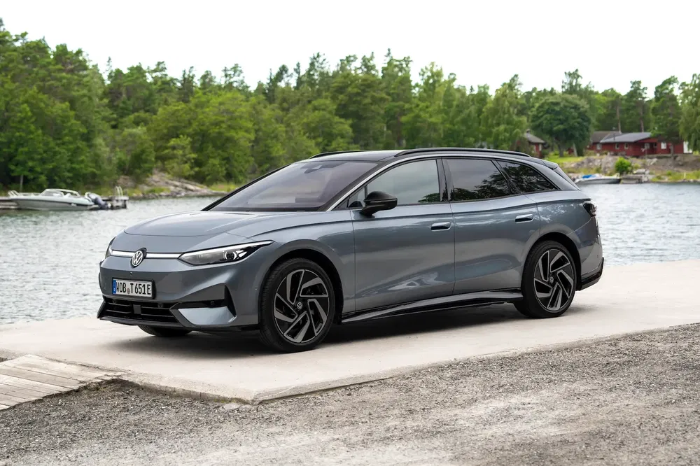 Volkswagen électrique break ID.7 stationné au bord d'un lac, nature en arrière-plan.