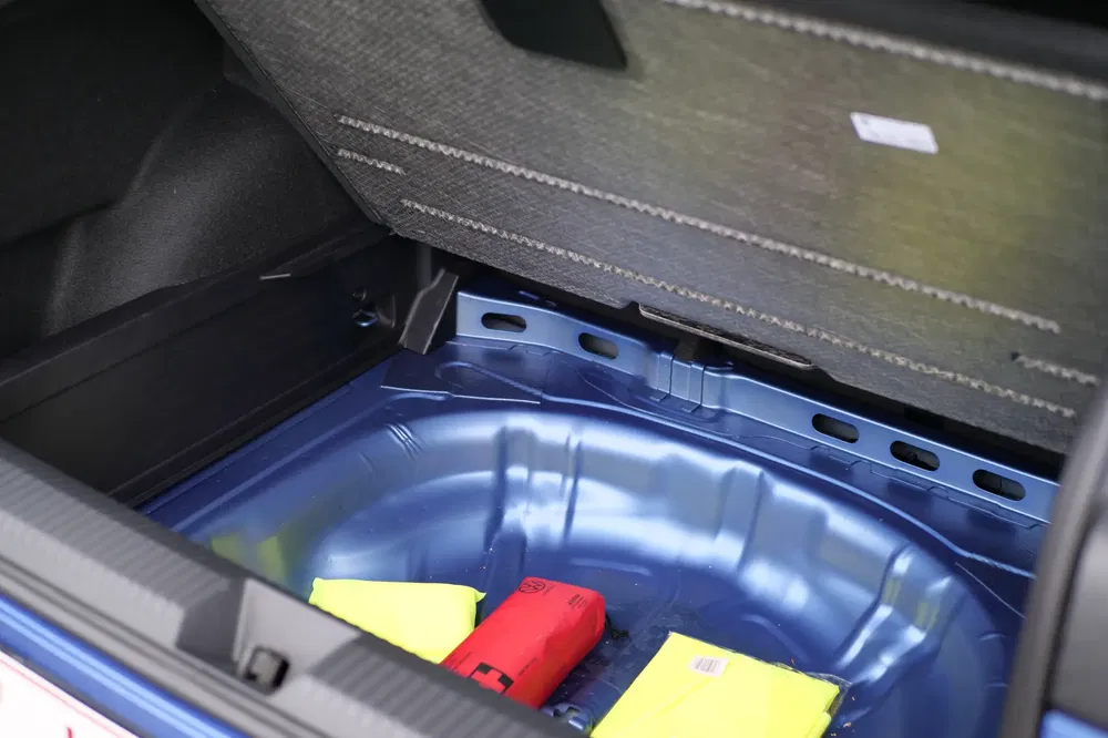 Kofferruimte van auto met veiligheidskit en ontbrekend reservewiel.