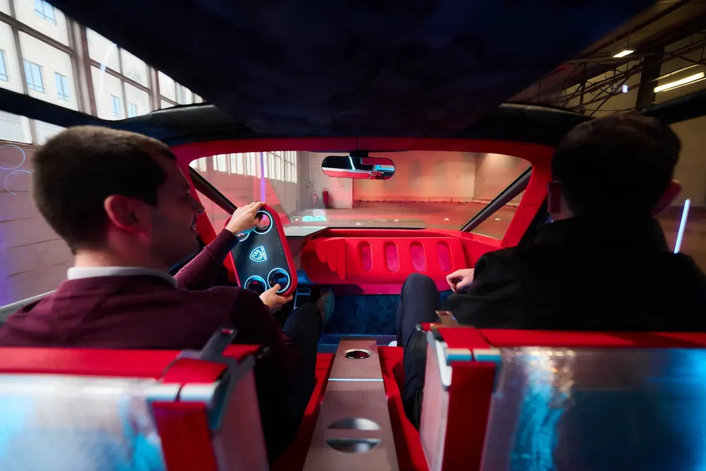 Intérieur d'une voiture électrique compacte avec tableau de bord rouge et conducteur concentré.