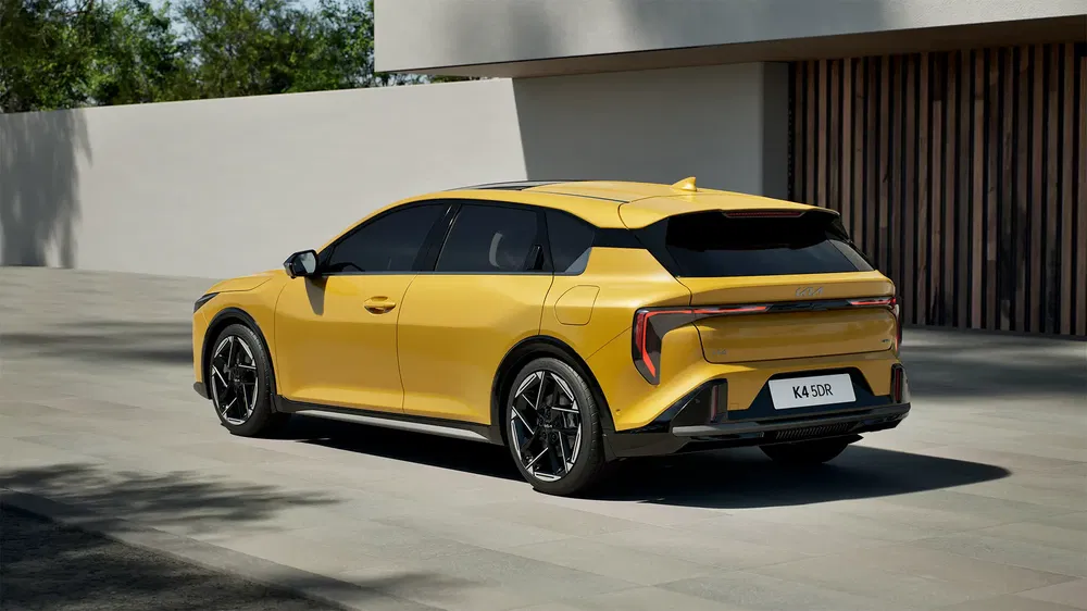 SUV électrique jaune Kia EV6 GT stationné sur une allée moderne, éclairage naturel.